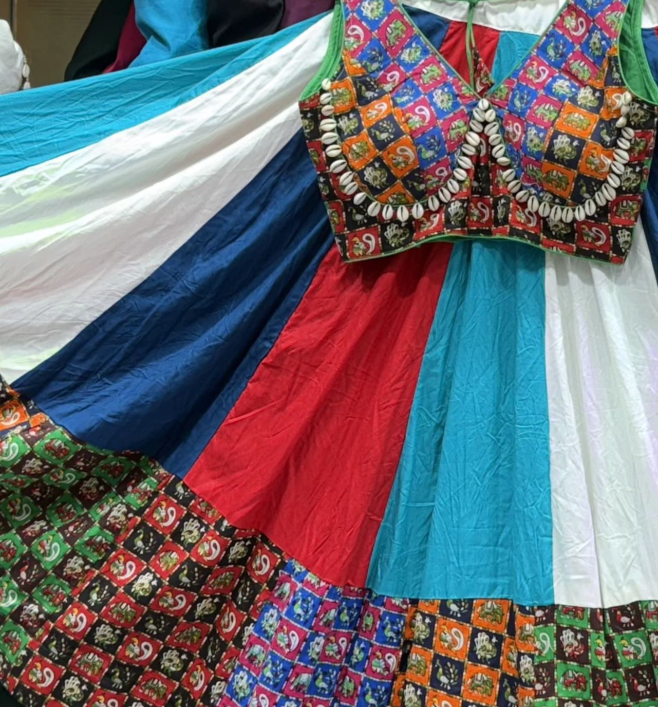Colorful traditional outfit with a patterned blouse and multicolored skirt.