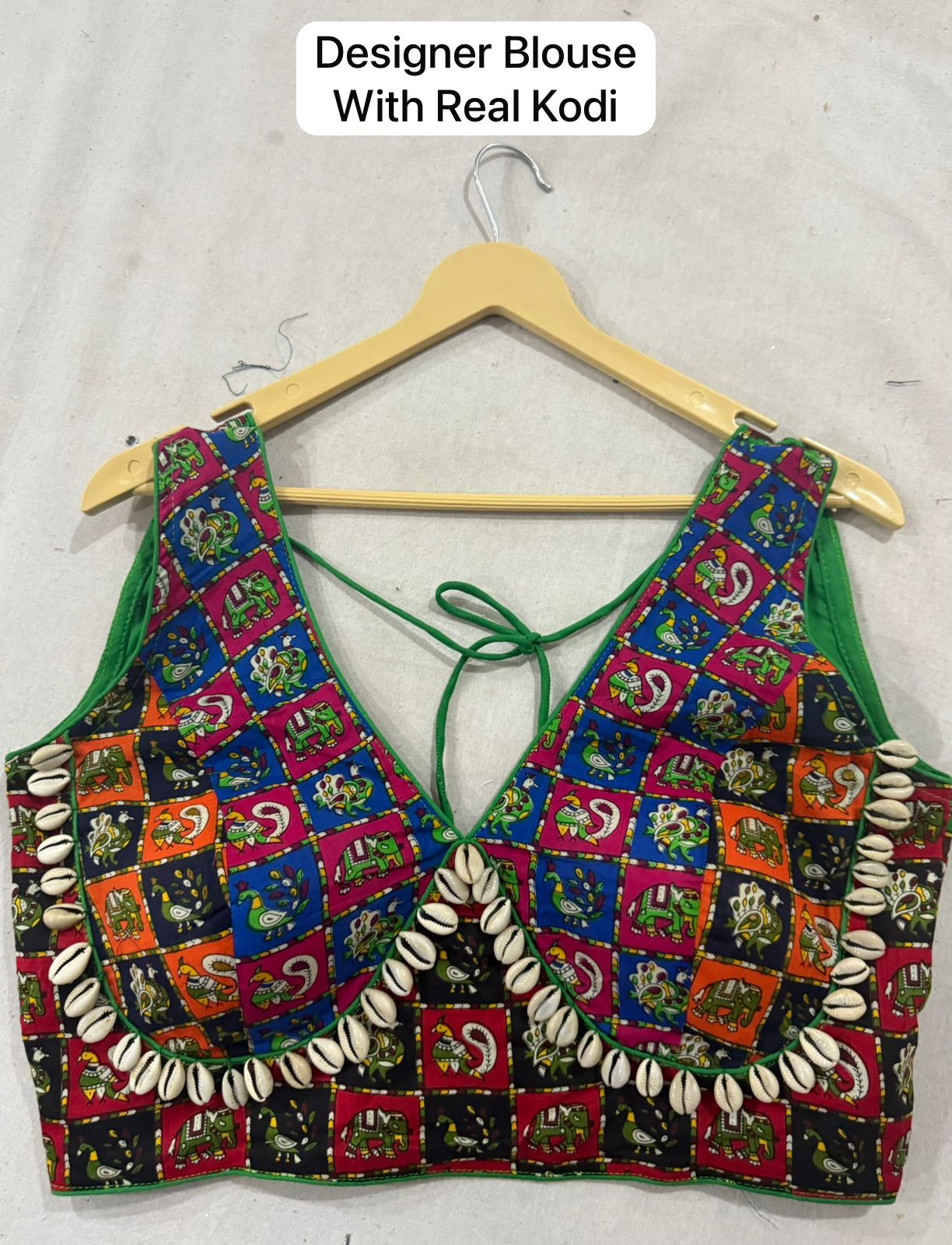 Colorful blouse with shell details on a hanger against a white background